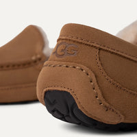 Close-up of brown suede shoes with a visible brand logo on a white background