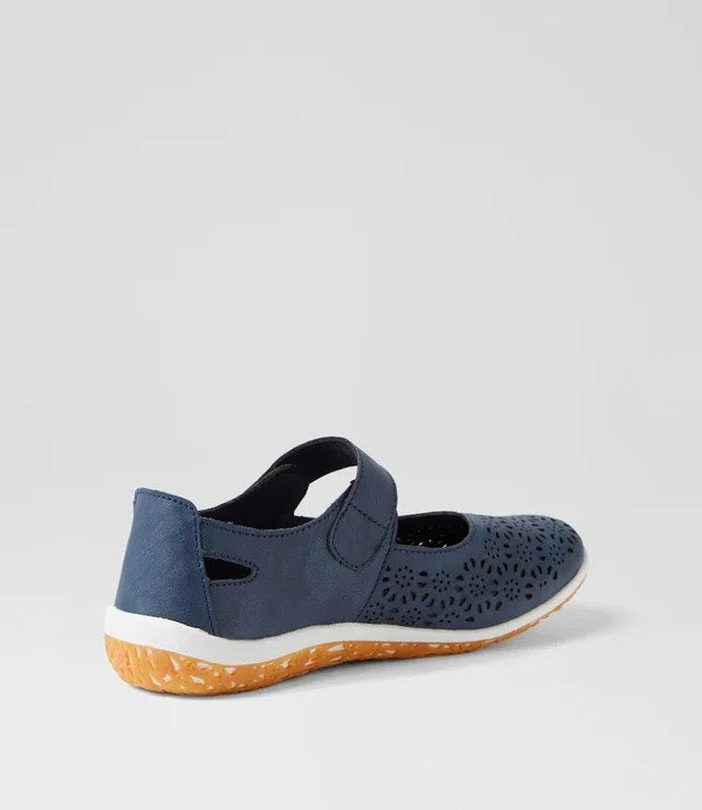 A navy blue Mary Jane-style shoe with a perforated upper, hook-and-loop strap, and a textured orange-brown sole, shown from a side-rear angle on a light gray background.