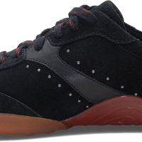 A black suede and synthetic leather sneaker with a translucent brown gum sole, a white heel tab, and red laces, shown from a side profile on a white background.